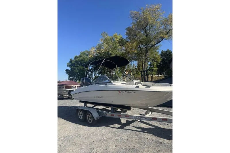 Slide: The Image of 2016 Stingray 191DC (OB) boat on trailer, parked outdoors under clear sky. - 3