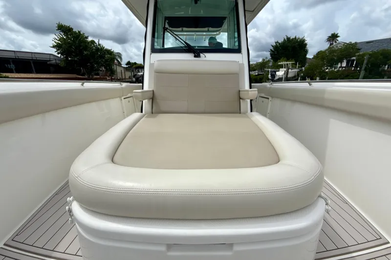 Slide: The Image of 2019 Boston Whaler 330 Outrage boat with cushioned seating, docked under cloudy skies. - 11