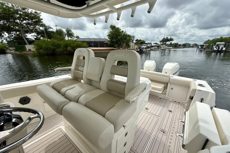 Slide: The Image of 2019 Boston Whaler 330 Outrage boat interior with luxurious seating and scenic waterway view. - 14