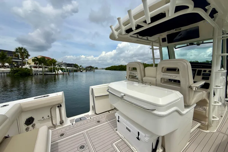 Slide: The Image of 2019 Boston Whaler 330 Outrage boat interior with seating, console, and scenic waterfront view. - 15