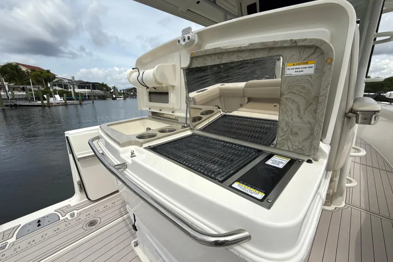 Slide: The Image of 2019 Boston Whaler 330 Outrage boat with outdoor grill and seating area by the water. - 17