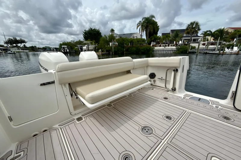Slide: The Image of 2019 Boston Whaler 330 Outrage boat with foldable seating, docked by a scenic waterfront. - 18