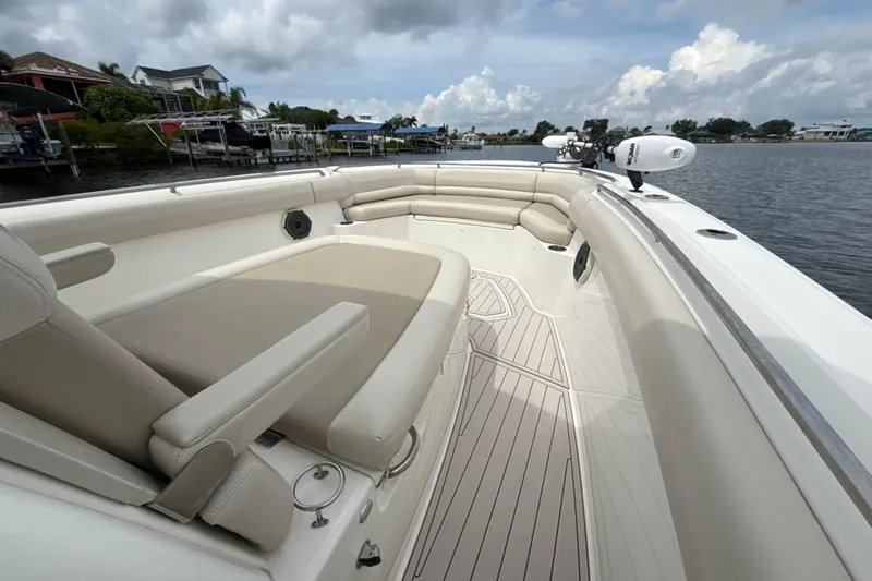 Slide: The Image of 2019 Boston Whaler 330 Outrage boat interior with cushioned seating and scenic waterfront view. - 6