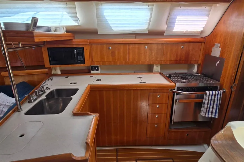 Slide: The Image of 2003 Hunter 386 yacht kitchen with wooden cabinetry, stainless steel sink, and modern appliances. - 16
