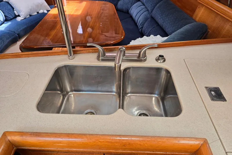 Slide: The Image of Galley sink in 2003 Hunter 386 yacht with wooden dining area and blue seating. - 19