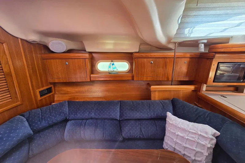 Slide: The Image of Interior of 2003 Hunter 386 sailboat with wooden cabinets and blue cushioned seating. - 23