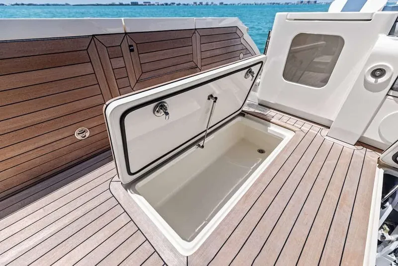 Slide: The Image of Open storage compartment on 2026 Scout 670 LX boat deck, with wood finish and ocean view. - 16