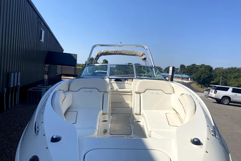 Slide: The Image of 2008 Sea Ray 260 Sundeck boat with white seating, parked outdoors under clear blue sky. - 2