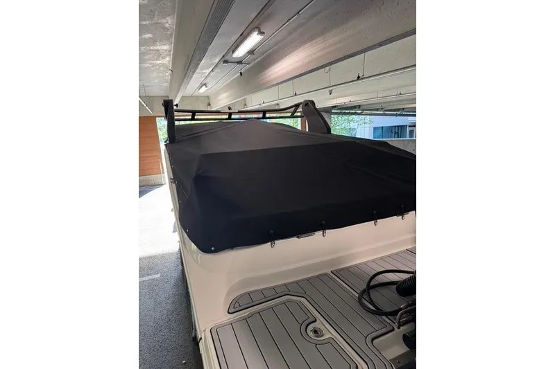 Slide: The Image of 2019 Sea Ray SDX 290 Outboard covered in a garage, showcasing rear deck and protective cover. - 13