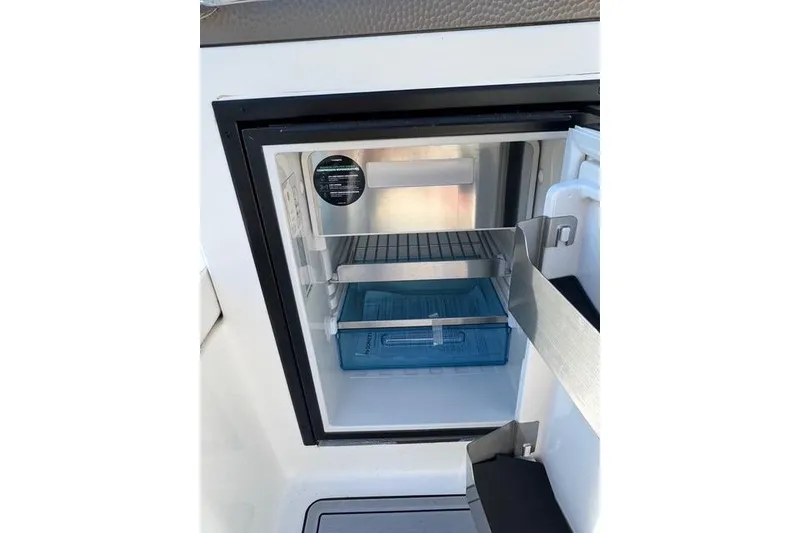 Slide: The Image of Open mini fridge on 2019 Sea Ray SDX 290 Outboard boat, showing interior shelves. - 26