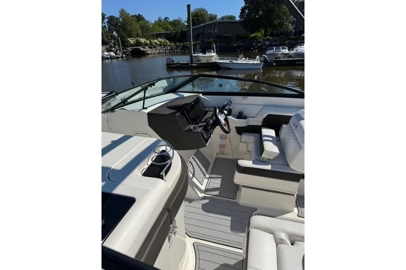 Slide: The Image of 2019 Sea Ray SDX 290 Outboard boat interior with helm, seating, and waterfront view. - 9