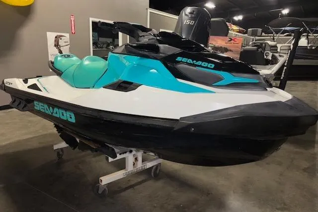 Slide: The Image of 2021 Sea-Doo GTX jet ski in showroom, featuring turquoise and black design. - 2