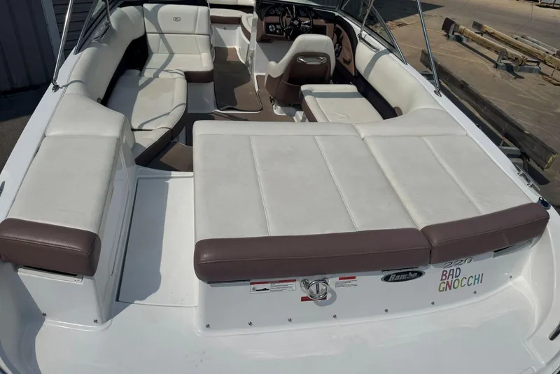 Slide: The Image of 2013 Cobalt 220 boat interior with white and brown seating, docked outdoors. - 12