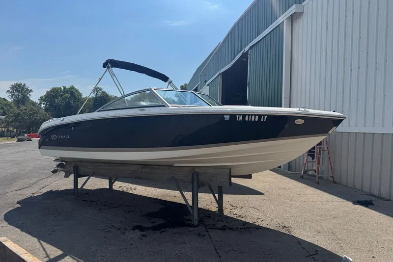 Slide: The Image of 2013 Cobalt 220 boat on a stand outside a metal building. - 2