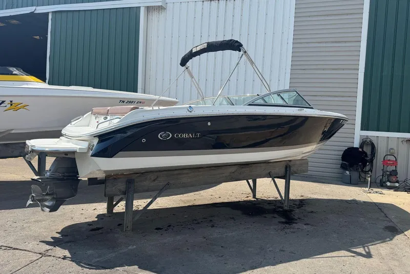 Slide: The Image of 2013 Cobalt 220 boat on a stand, displayed outdoors near a warehouse. - 4