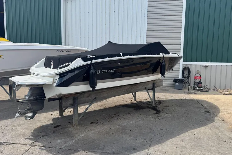 Slide: The Image of 2013 Cobalt 220 boat on stand, covered, near industrial building. - 40