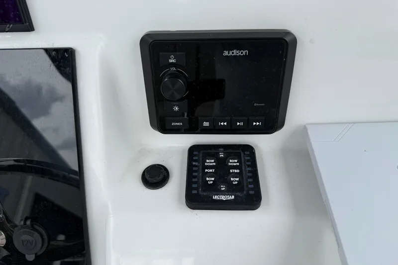 Slide: The Image of 2023 Sea Pro 248 Bay boat control panel with Audison audio system and Lectrotab trim tab controls. - 15