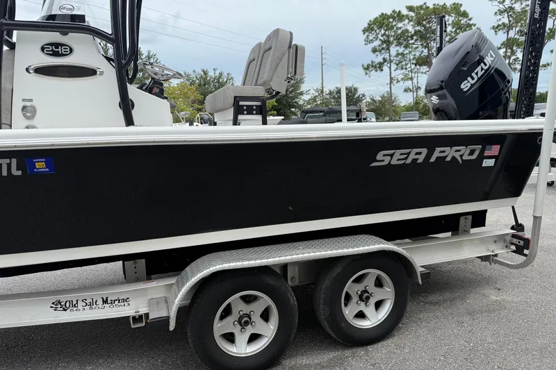 Slide: The Image of 2023 Sea Pro 248 Bay boat on trailer with Suzuki engine, parked outdoors. - 27