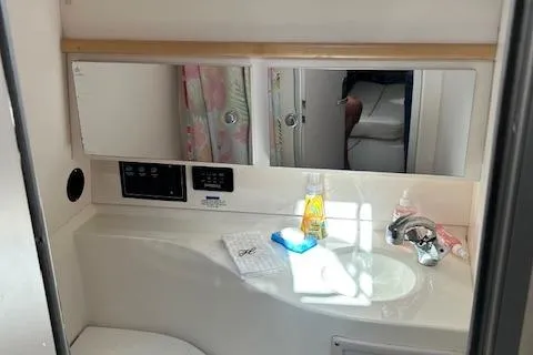 Slide: The Image of 2001 Wellcraft 330 Coastal bathroom with sink, mirror, and toiletries. - 9