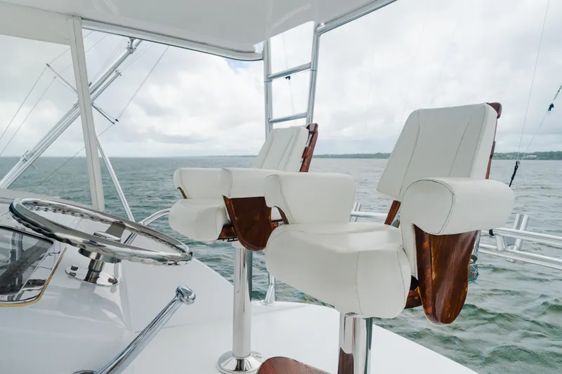Slide: The Image of 2005 Hatteras Convertible 60 yacht helm with luxurious white captain chairs and ocean view. - 40
