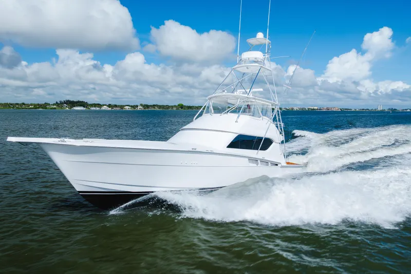 Slide: The Image of 2005 Hatteras Convertible 60 yacht cruising on open water under a clear blue sky. - 58