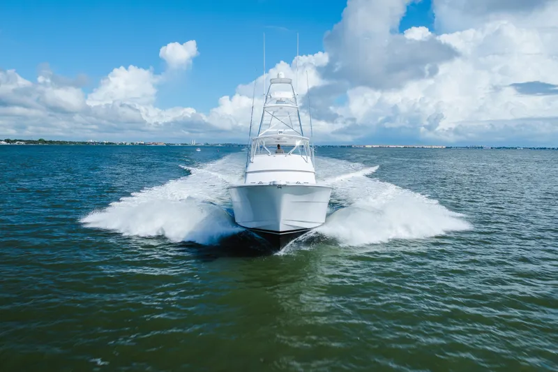 Slide: The Image of 2005 Hatteras Convertible 60 yacht cruising on open water under a blue sky. - 59