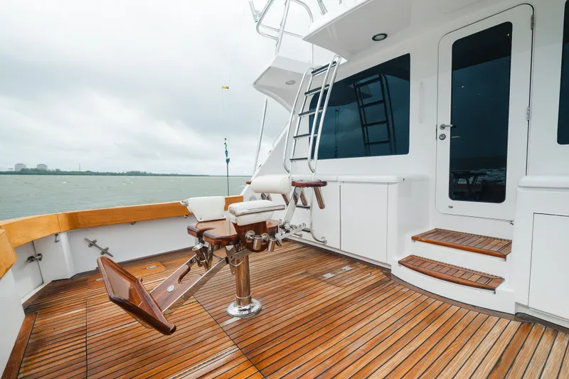 Slide: The Image of 2005 Hatteras Convertible 60 yacht deck with fishing chair and wooden flooring. - 6