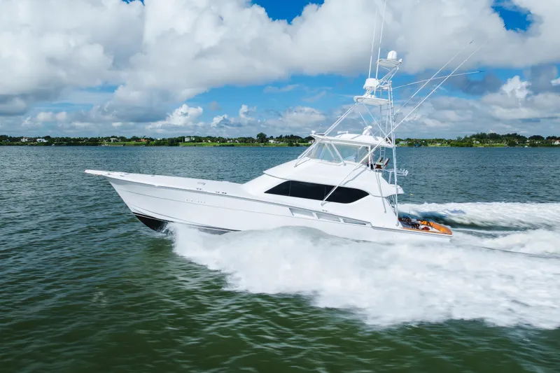 Slide: The Image of 2005 Hatteras Convertible 60 yacht cruising on open water under a cloudy sky. - 60
