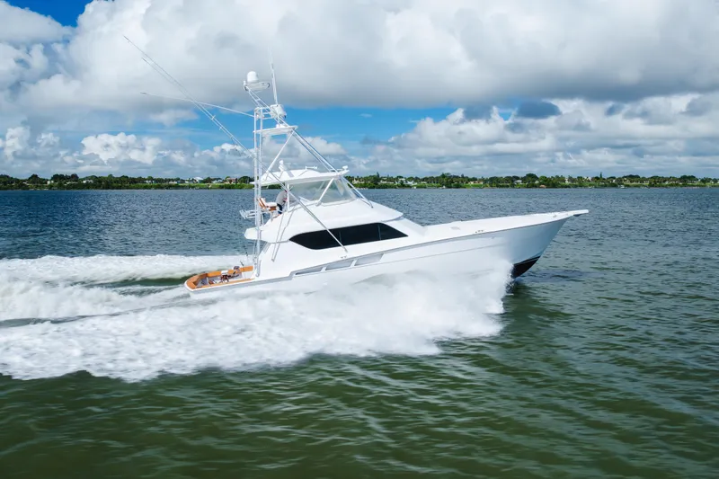 Slide: The Image of 2005 Hatteras Convertible 60 yacht cruising on open water under a cloudy sky. - 66