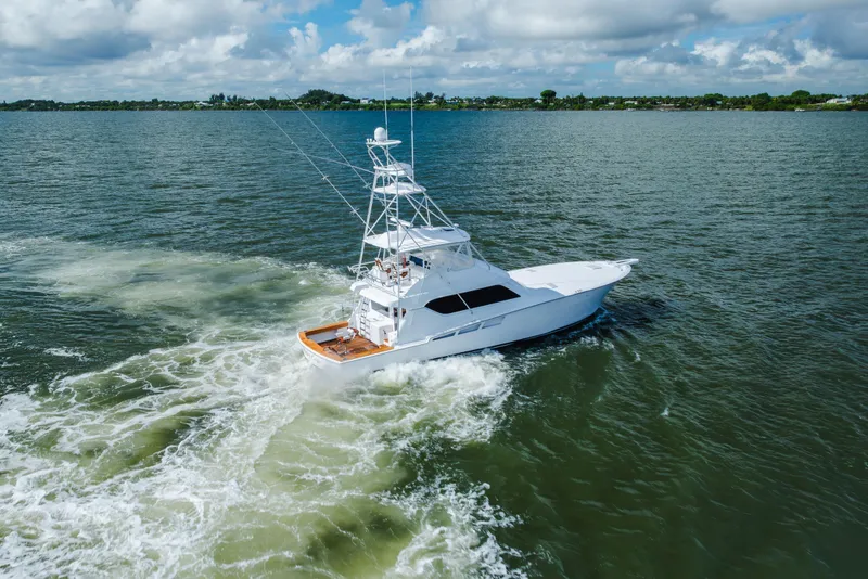 Slide: The Image of 2005 Hatteras Convertible 60 yacht cruising on open water under cloudy skies. - 68