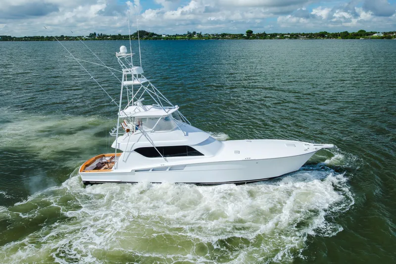 Slide: The Image of 2005 Hatteras Convertible 60 yacht cruising on open water under a cloudy sky. - 69