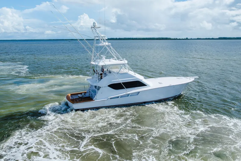 Slide: The Image of 2005 Hatteras Convertible 60 yacht cruising on open water under a cloudy sky. - 70