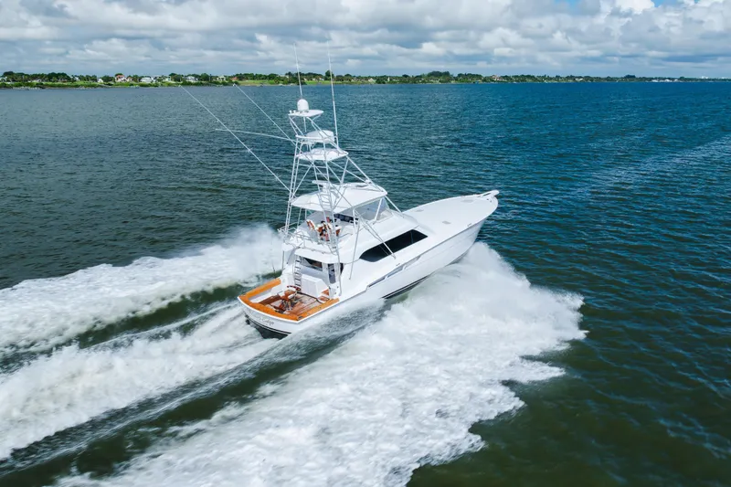 Slide: The Image of 2005 Hatteras Convertible 60 yacht cruising on open water under cloudy skies. - 71