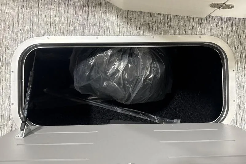 Slide: The Image of Open storage compartment in 2025 Bennington 27QXSBWAT2 boat, showing interior contents. - 5
