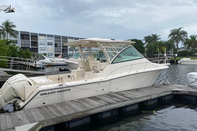 Slide: The Image of 2022 Grady-White Express 370 boat docked at marina with palm trees and buildings. - 1