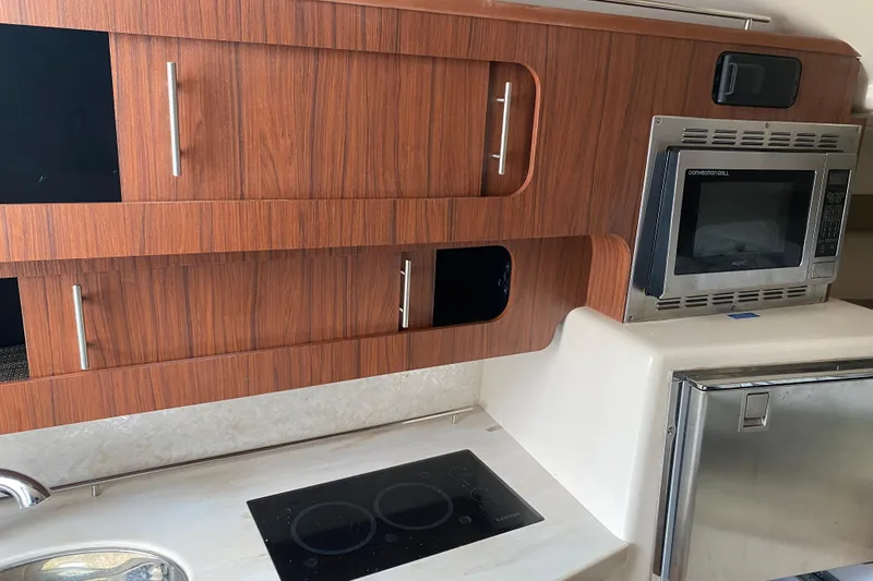 Slide: The Image of 2022 Grady-White Express 370 kitchen with wood cabinets, microwave, and stovetop. - 13