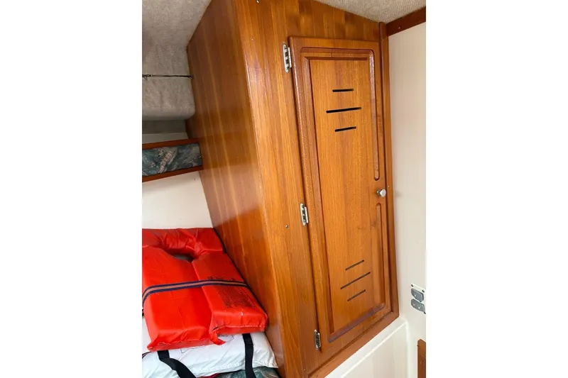 Slide: The Image of 2005 Carolina Classic 25 interior with wooden cabinet and life jackets. - 15