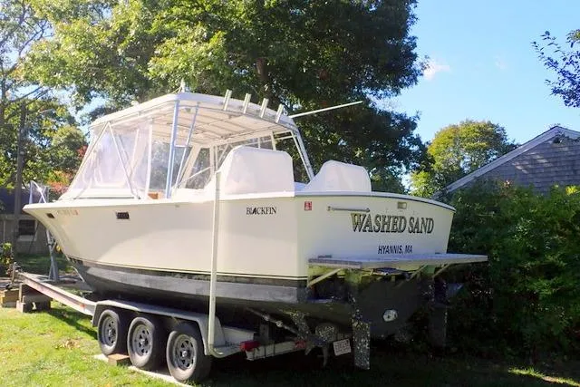Slide: The Image of 1989 Blackfin 27 Fisherman boat on trailer, named "Washed Sand," in a sunny yard. - 17