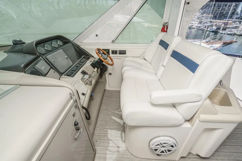 Slide: The Image of 2005 Sea Ray 390 Motor Yacht helm with white seating and control panel. - 16