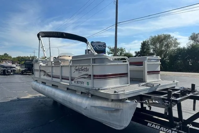 Slide: The Image of Sweetwater 2019 EL pontoon boat on trailer, parked outdoors, clear sky background. - 3