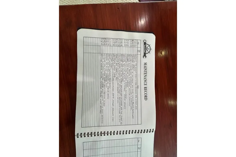 Slide: The Image of Maintenance record book for 2001 Crosswater Passagemaker 49, open on a wooden table. - 44