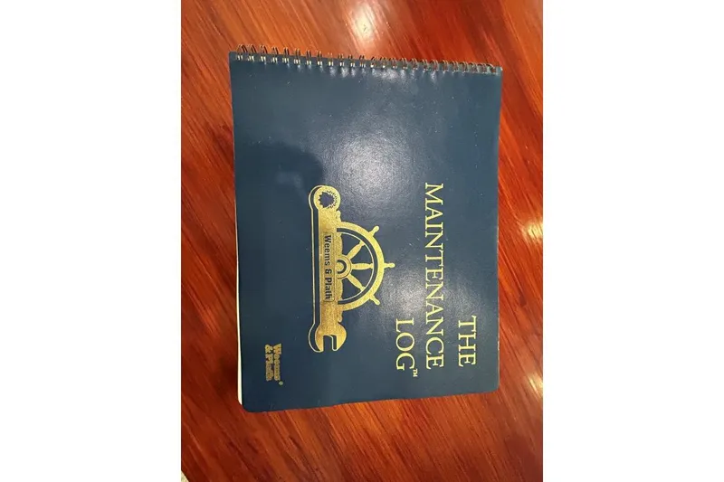 Slide: The Image of Blue maintenance logbook for Crosswater Passagemaker 49, 2001 model, on wooden surface. - 45