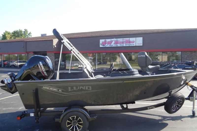 Slide: The Image of 2026 Lund 1650 Rebel XL SS boat with Mercury engine on trailer, parked outside dealership. - 12