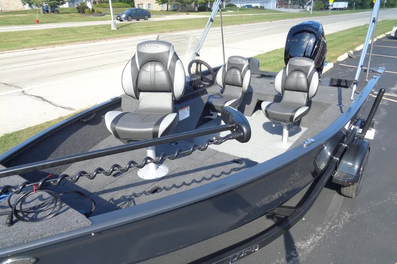 Slide: The Image of 2026 Lund 1650 Rebel XL SS fishing boat with three seats and motor, parked on pavement. - 26