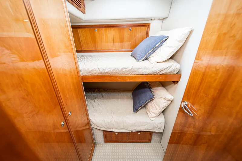 Slide: The Image of 2009 Riviera 47 Open Flybridge Series II cabin with wooden bunk beds and blue pillows. - 53