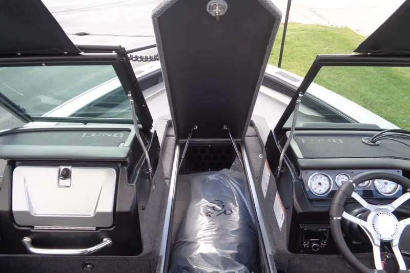 Slide: The Image of 2026 Lund 2075 Pro-V Sport boat interior with open storage compartments and dashboard controls. - 18