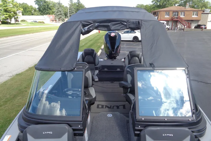 Slide: The Image of 2026 Lund 2075 Pro-V Sport boat with canopy, windshield, and seating, parked on pavement. - 20