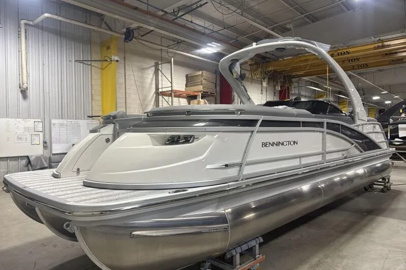 Slide: The Image of 2024 Bennington 25QFBWA pontoon boat in a warehouse setting. - 2