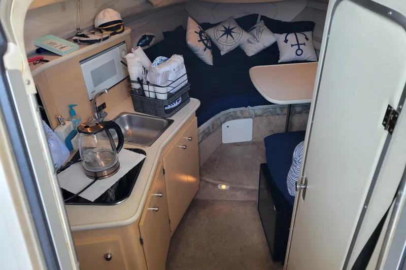 Slide: The Image of 2001 Bayliner 2655 Ciera cabin interior with kitchenette, seating, and nautical-themed decor. - 8