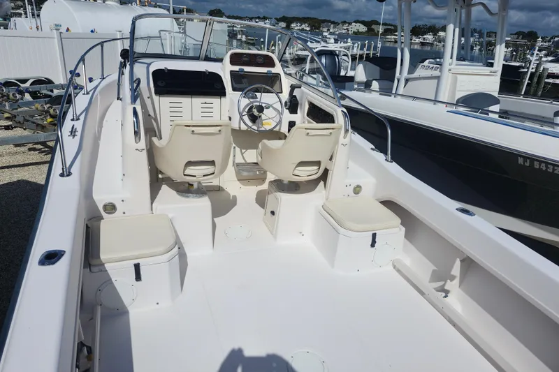 Slide: The Image of 2000 Grady-White Adventure 208 boat interior with seating and steering wheel, docked at marina. - 2
